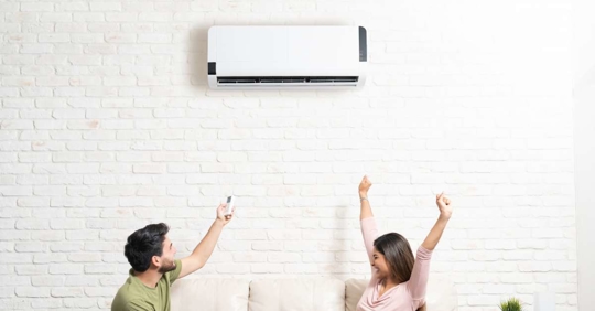 Couple sitting below mini split on a sofa at home