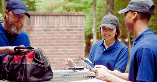 Air conditioner repairmen work on home unit